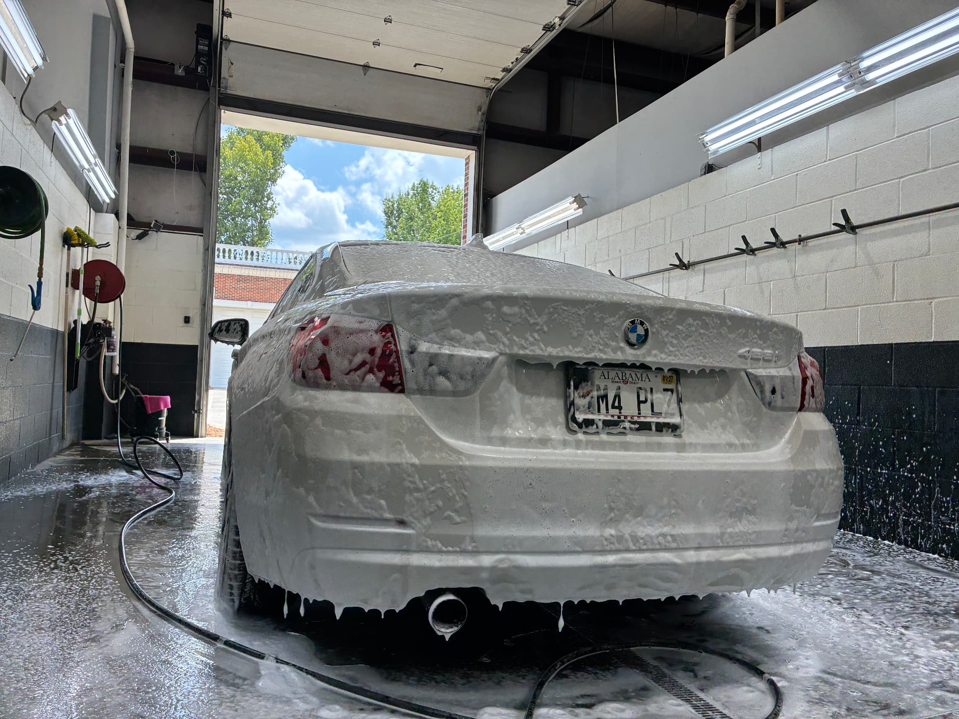 White BMW coupe covered in wash foam, Alabama plate M4 PLZ